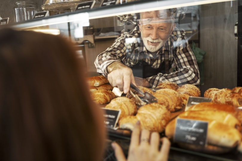 Man selects croissant at bakery.