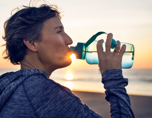 Jogger drinks water by beach.