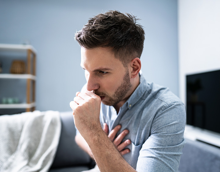 Young man coughing and experiencing chest pain.