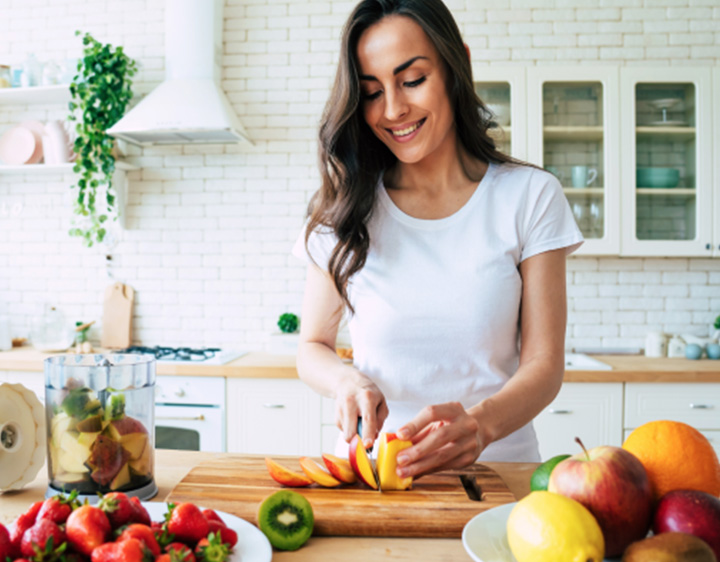 Woman in kitchen making fruit salad.